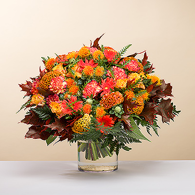 Les teintes flamboyantes de l'automne s'expriment dans ce bouquet vibrant et luxueux, créé à la main, dans des tons orange, bordeaux, rose vif et jaune.